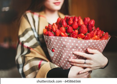 Bouquet of strawberries close-up in the hands of a girl