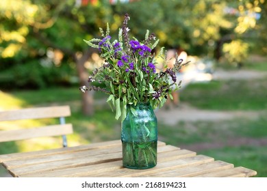 Bouquet of summer flowers in ceramic vase on table on terrace. Fresh Field flowers in vase. Cozy home decor of patio yard. Still life. Women day or wedding concept. festive background, copy space