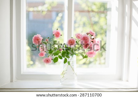 Bouquet of summer roses in glass vase near the window 