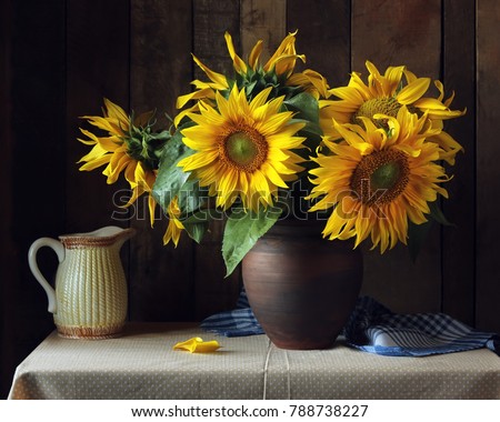 Bouquet of sunflowers in a clay jug on the table on the wooden background. Still life in rustic style.