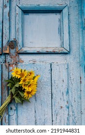 Bouquet of sunflowers on a blue wooden background. Old blue wooden door with yellow flowers. Copy space