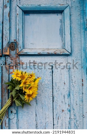 Bouquet of sunflowers on a blue wooden background. Old blue wooden door with yellow flowers. Copy space