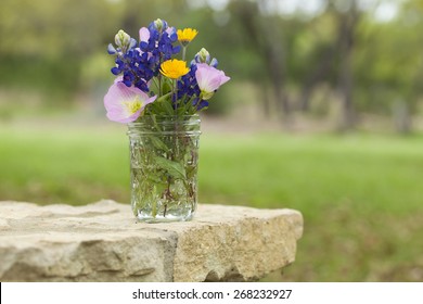 A bouquet of Texas wildflowers from the Texas Hill Country in a mason jar on a stone wall. Evening primroses, bluebonnets and yellow daisies. - Powered by Shutterstock