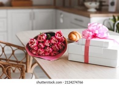 Bouquet of tulips and gift boxes for International Women's Day celebration on dining table, closeup