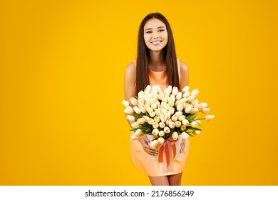 Bouquet Of Tulips In The Hands Of A Beautiful Girl. Happy Asian Woman With Flowers Bouquet On A Yellow Background. Flower Delivery Concept.