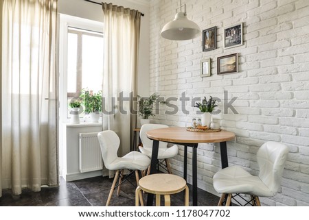 Bouquet of tulips in interior of the kitchen in Scandinavian style with white furniture and a dining table. All photos in photo frames on whall made by me.