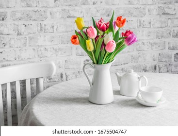 Bouquet of tulips , teapot and teacup on the table in the bright kitchen. Cozy home concept                    