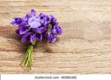 Bouquet of violet flowers (Viola Odorata) on wooden background, copy space