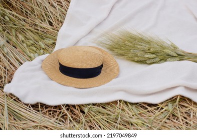 A Bouquet Of Wheat And A Hat On A White Bedspread