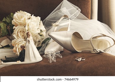 Bouquet of white roses, rings and satin wedding shoes on chair