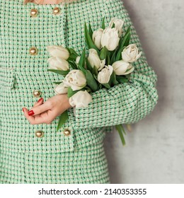 bouquet of white tulips in the hand of a girl in a tweed green suit, close-up view. girl holding flowers. spring concept, fresh spring colors - Shutterstock ID 2140353355