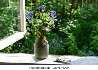 Bouquet of wild flowers in a vase on the window of an old country house, summer cottage. - Shutterstock ID 2287644909
