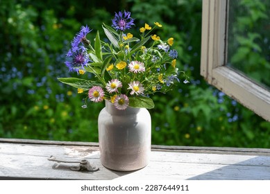 Bouquet of wild flowers in a vase on the window of an old country house, summer cottage. - Shutterstock ID 2287644911