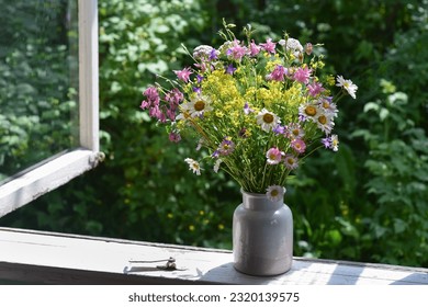 Bouquet of wildflowers in a vase on a wooden window sill. Floral decoration on the window of an old country house, summer cottage. Сountry life aesthetics. - Shutterstock ID 2320139575