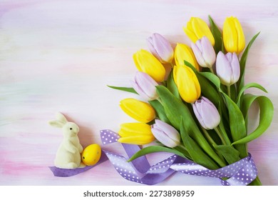 Bouquet of yellow and purple tulips with polka dot ribbon, rabbit and egg on colorful watercolor paper. Easter card, copy space. - Powered by Shutterstock