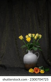 
Bouquet de rosas amarillas en un jarrón, jarra. Fondo de tela oscura. Cerca hay tres rosas. Colocar para una inscripción. vida de quietud de flores