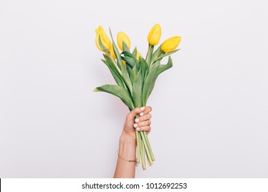 Bouquet of yellow tulips in a female hand on a white background