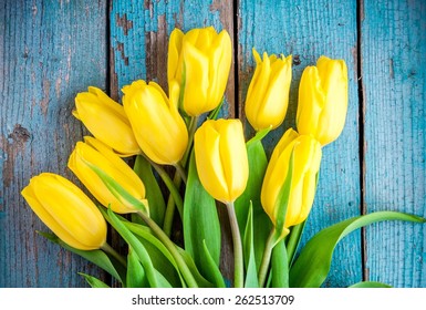 bouquet of yellow tulips on a blue wooden background