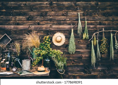 bouquets of different aromatic windflowers and glass bottles put on old wooden table standing near rustic wall of country house on autumn day