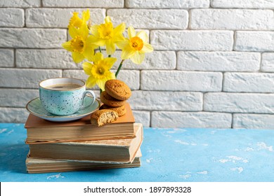 Bouquets Of Spring Flowers, Coffee Cup, Books, Cookies On Blue Table Over White Brick Background. Reading And Breakfast. Concept Spring, Hygge And Cozy Home. Copy Space
