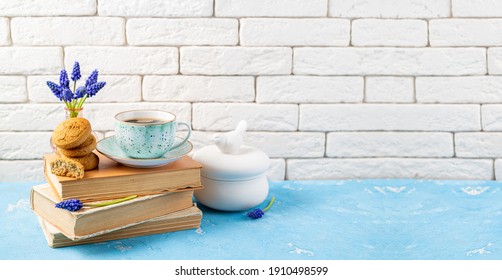 Bouquets Of Spring Flowers, Coffee Cup, Books, Cookies On Blue Table Over White Brick Background. Reading And Breakfast. Concept Spring, Hygge And Cozy Home Interior. Copy Space
