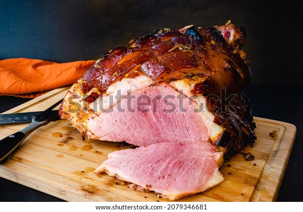Bourbon Orange Glazed Ham\
on a Bamboo Carving Board: Sliced bone-in glazed ham on a wooden\
cutting board