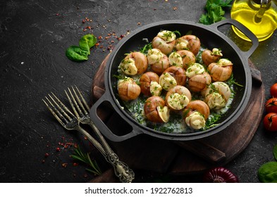 Bourgogne Escargot Snails with garlic, cheese in a creamy sauce on a black stone plate. Top view. Free space for text.