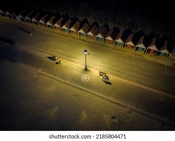 Bournemouth Beach Huts And Sandy Beach In Dorset, UK At Night With People Walking Along Beach In Evening Light - HDR