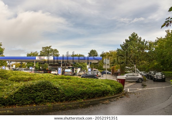 Bournemouth, UK- October 04 2021: People wait in a  long\
queue to fill their vehicles with fuel at the Tesco Extra service\
station whilst the delivery driver shortage continues across the\
country 
