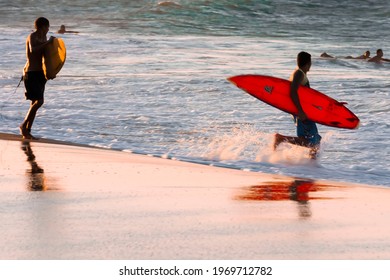 Bous with sufboards on the sea shore.