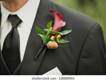 Boutonniere of acorn and calla lily on suit jacket of wedding groom