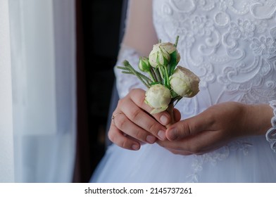 Boutonniere of the groom with flowers in the hands of the bride