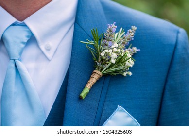 boutonniere made with lavender, rosemary, and babys breath tied with twine pinned to a blue jacket, blue tie, wedding day clothes