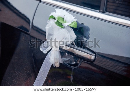 Boutonniere made of white flowers hanging on black wedding car handle