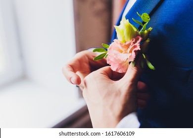 Boutonniere on groom's wedding jacket. White and pink rose wedding boutonniere on suit of groom.