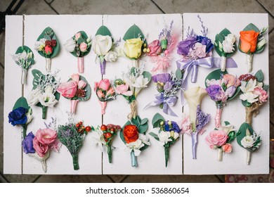 Boutonniered of roses lie in rows on white table - Shutterstock ID 536860654