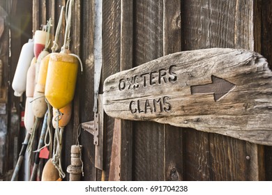 Bouys And A Sign For Oysters And Clams Hang On A Shed At A Shellfish Farm On Orcas Island, Washington. 
