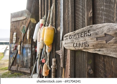 Bouys And A Sign For Oysters And Clams Hang On A Shed At A Shellfish Farm On Orcas Island, Washington. 