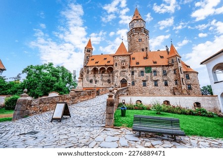 Bouzov castle. Fairytale castle in czech highland landscape. Castle with white church, high towers, red roofs, stone walls. Czech republic.