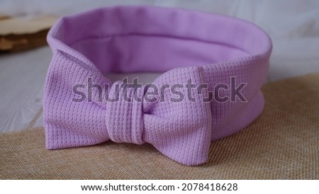 Bow headband made out of knit fabric with beautiful texture in soft purple color. A hair accessory with bow in front.