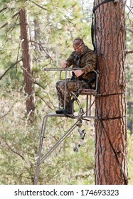 Bow Hunter In A Ladder Style Tree Stand Demonstrating Safe Practices By Using A Safety Harness And A Haul Line