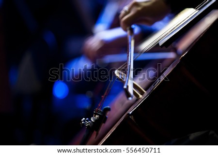 The bow on the strings of the cello closeup in dark colors