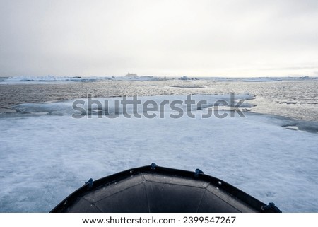 Bow of a ridged hull inflatable boat motoring though floating sea ice in the polar north on the arctic ocean, a symbol of climate change and global warming
