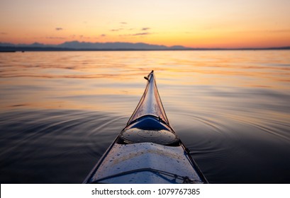 Bow of sea kayak at sunset pointed at Bainbridge Island and the Olympic Mountains, Puget Sound, Seattle, WA USA