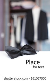 Bow Tie In Front Of Open Closet And Tuxedo With Isolated Place For Text.