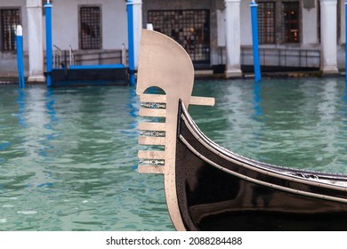 Bow of a Venetian gondola with the traditional iron comb shaped on the bow on the waters of a canal. Venice gondola for romantic trips through the canals of the city and on the Grand Canal.