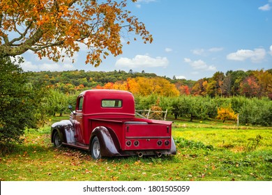 Bowdoin, Maine - October 12, 2018: Old Antique Red Farm Truck In Apple Orchard Against Autumn Landscape Background. Blue Sky On A Sunny Fall Day In New England.