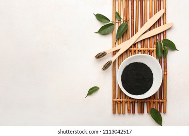 Bowl with activated charcoal tooth powder and brushes on white background