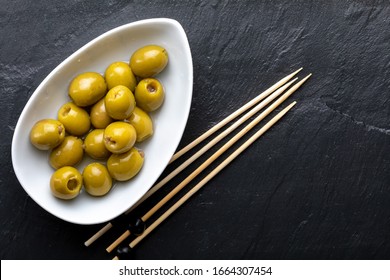 Bowl With Anchovy Stuffed Olives. On Black Slate. Blackboard. Toothpick. Top View.