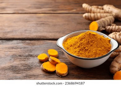 Bowl with aromatic turmeric powder and cut roots on wooden table. Space for text - Shutterstock ID 2368694187